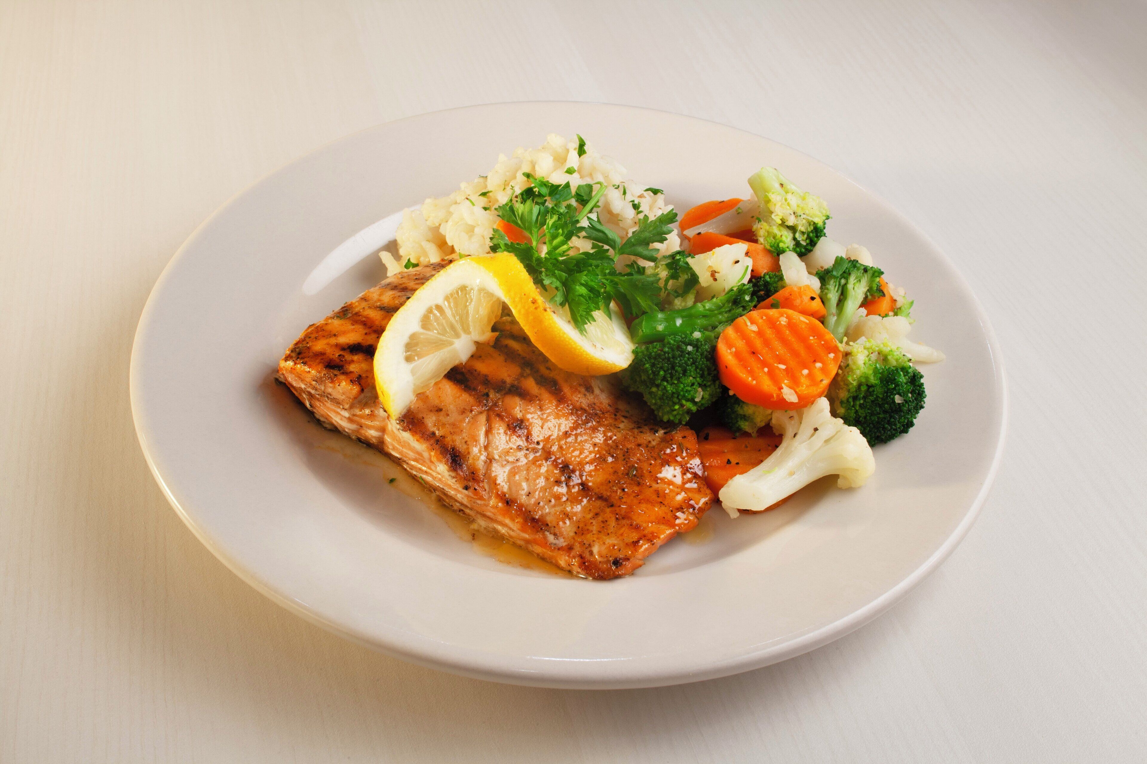 Une assiette contenant du saumon grillé, des brocolis, des carottes et du chou-fleur.