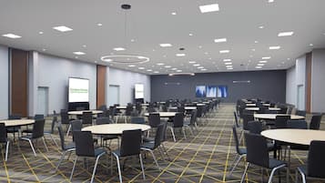 Une salle de conférence dotée de plusieurs tables et chaises, d’un sol recouvert de moquette et d’un écran de projection à l’arrière.