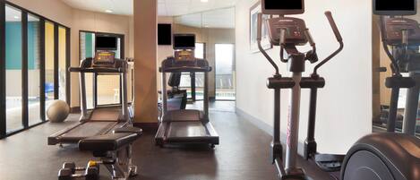 A gym with treadmills, elliptical machines, and free weights.