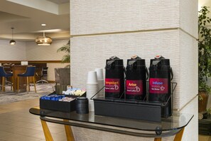 Angolo caffè con tre erogatori etichettati 'Jumpstart', 'Arise' e 'Infuse' per caffè e acqua calda.