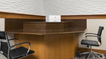 A corner office with a wooden desk, two black office chairs, and a white HP printer.