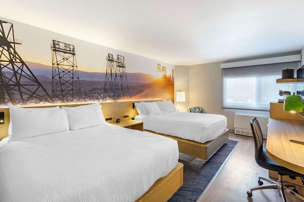 A hotel room with two beds, a desk, and a large mural of industrial structures.