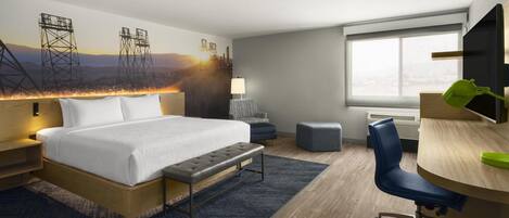 Habitación de hotel con una cama grande, un escritorio, una silla, una lámpara y una ventana.