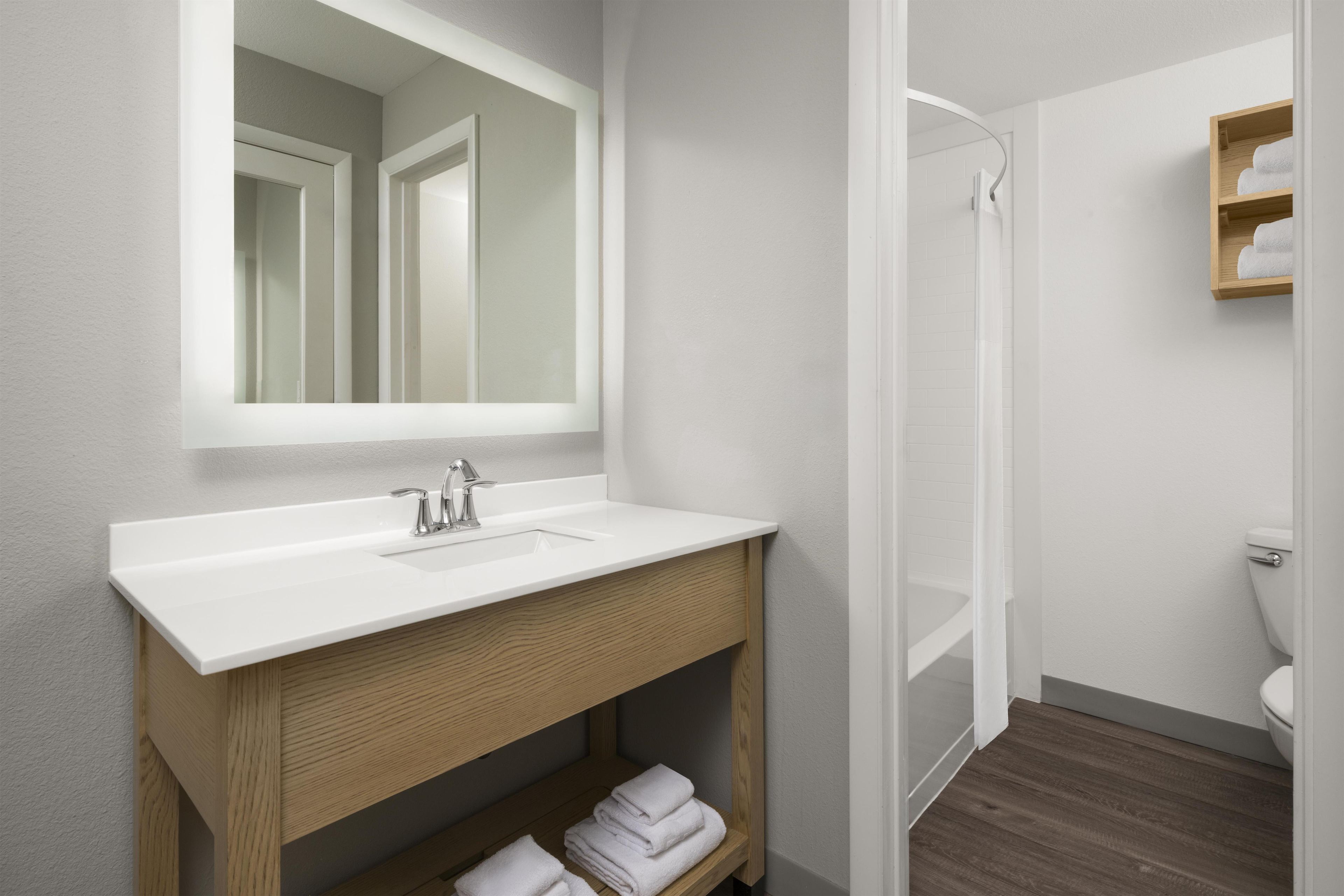 A modern bathroom with a white sink, wooden vanity, and a glass shower enclosure.