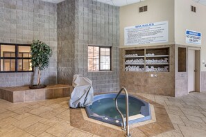 A spa area with a hot tub, a sign detailing spa rules, and a shelf with towels.