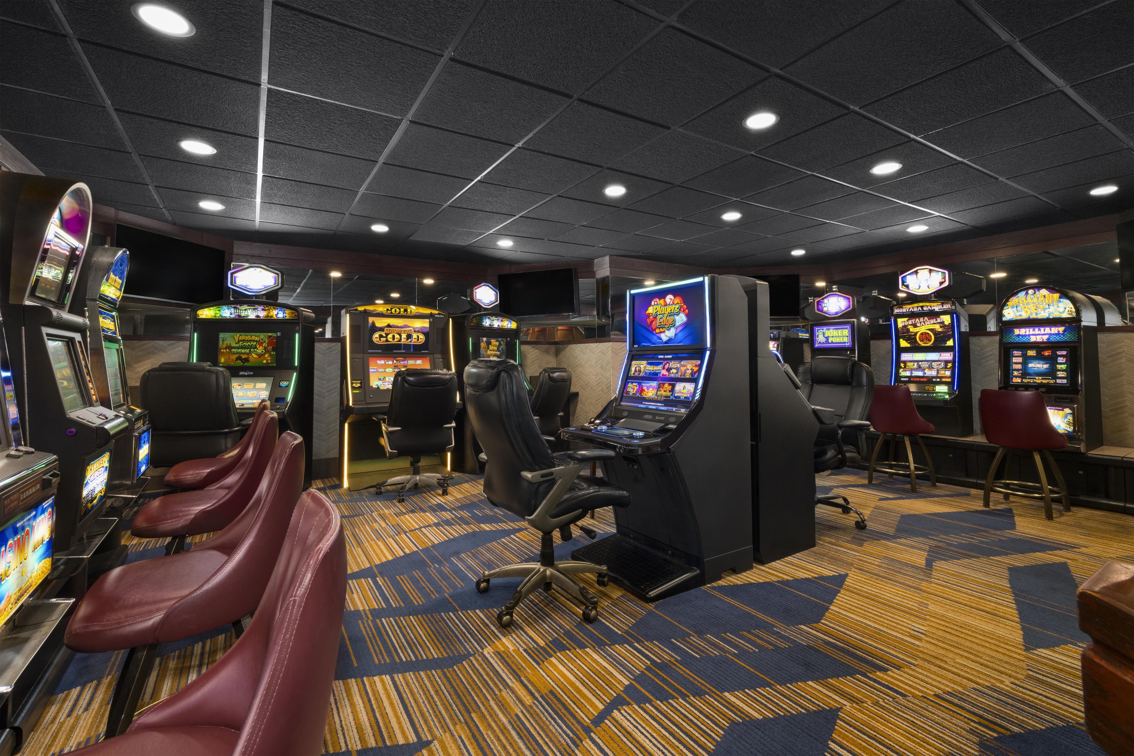 A casino gaming area with multiple slot machines, gaming tables, and comfortable seating.