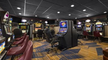 A casino gaming area with multiple slot machines, gaming tables, and comfortable seating.