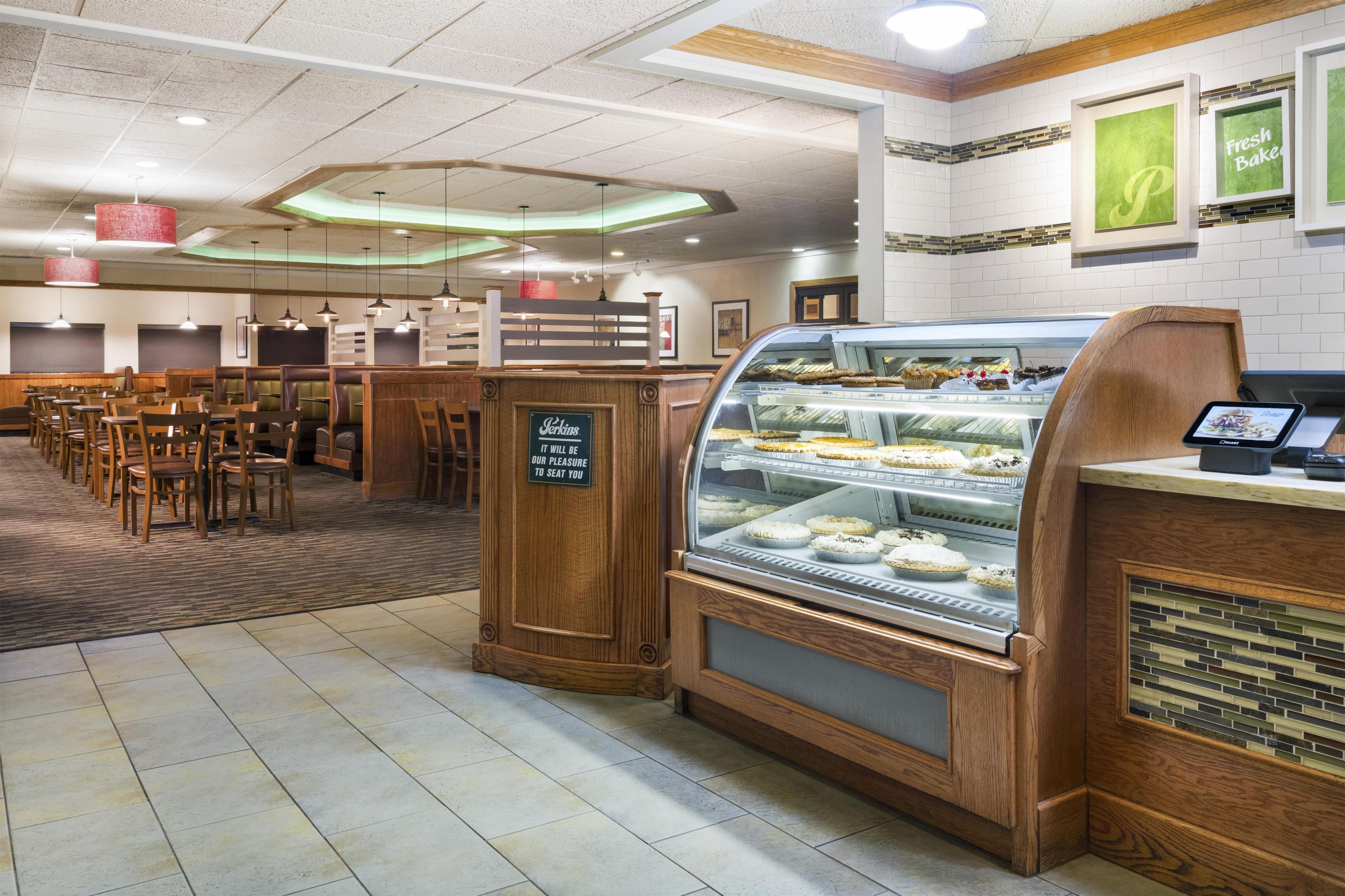 A bakery display case with various baked goods, a seating area with tables and chairs, and a sign indicating the bakery's name.