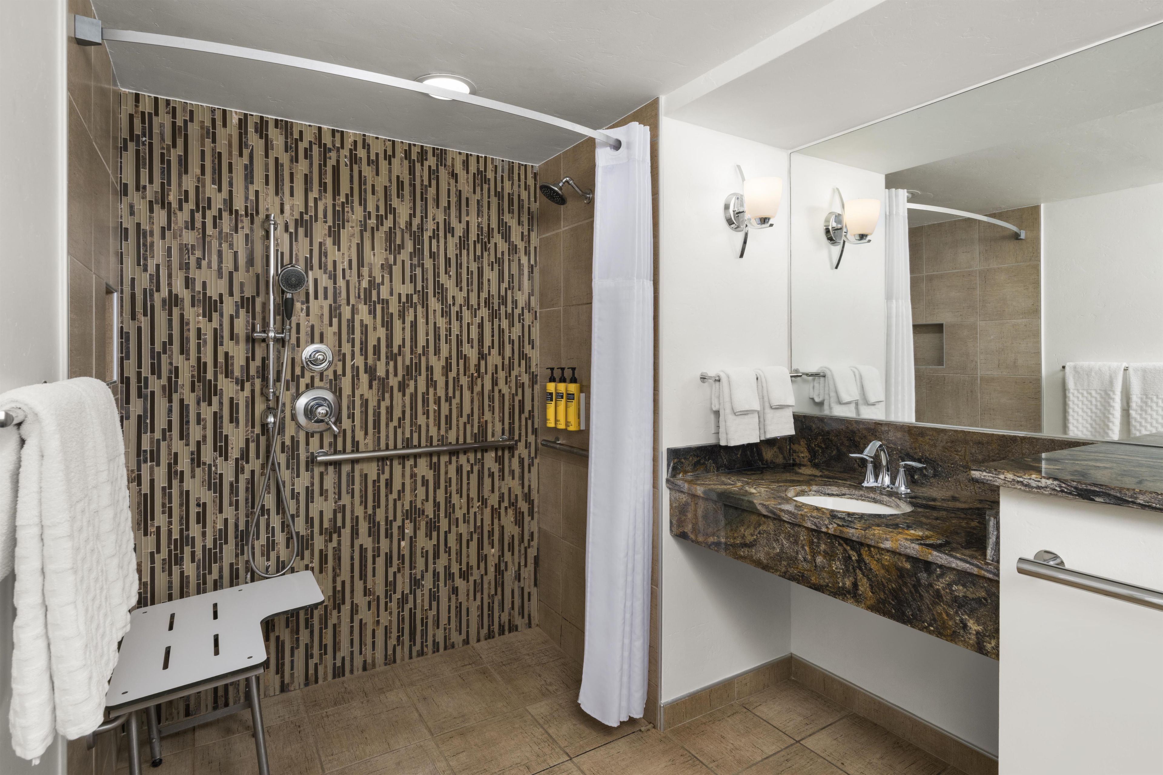 A modern bathroom with a shower, a vanity with a sink, and a mirror.