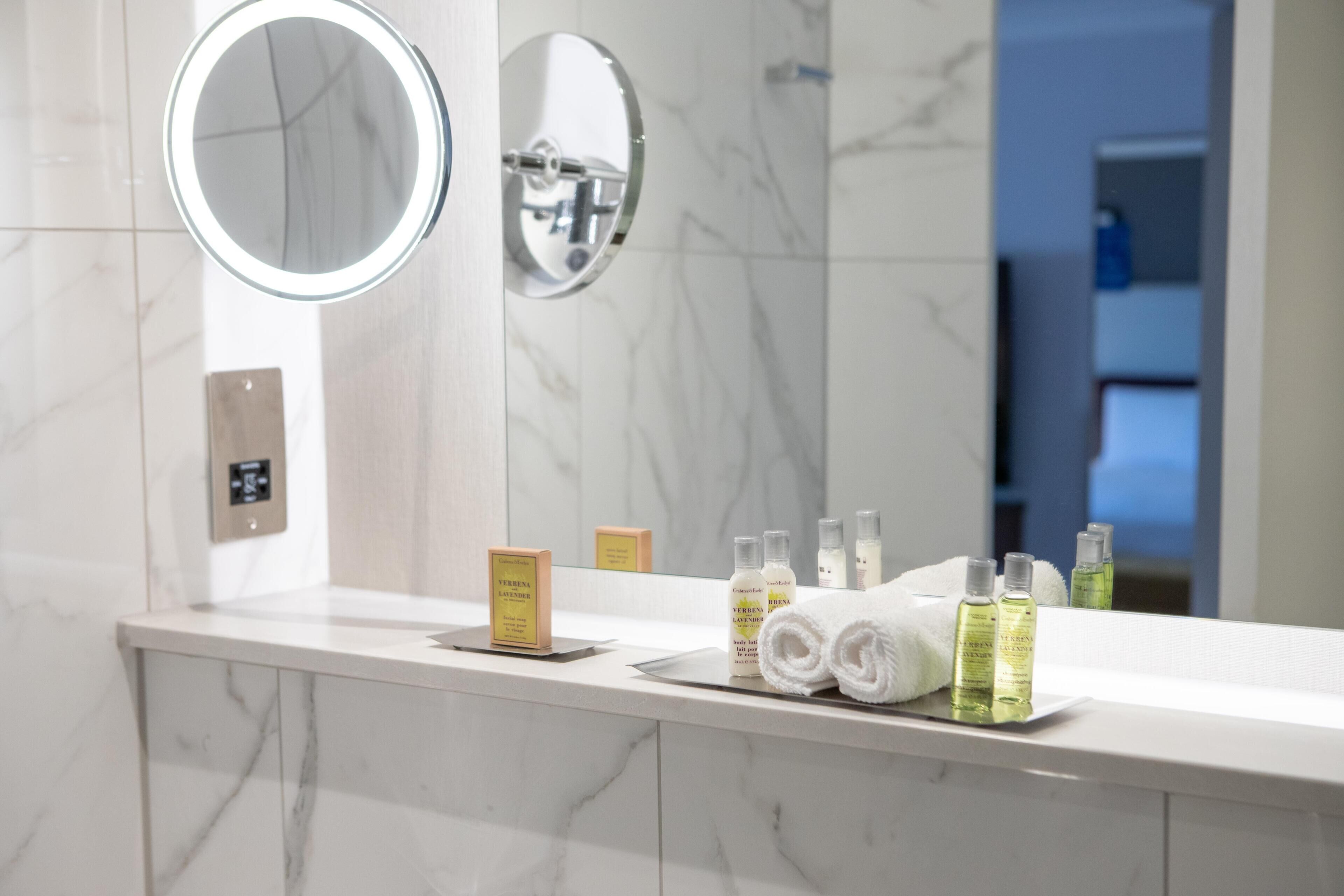 Un bagno con top in marmo, due specchi, un porta asciugamani e articoli da toilette.