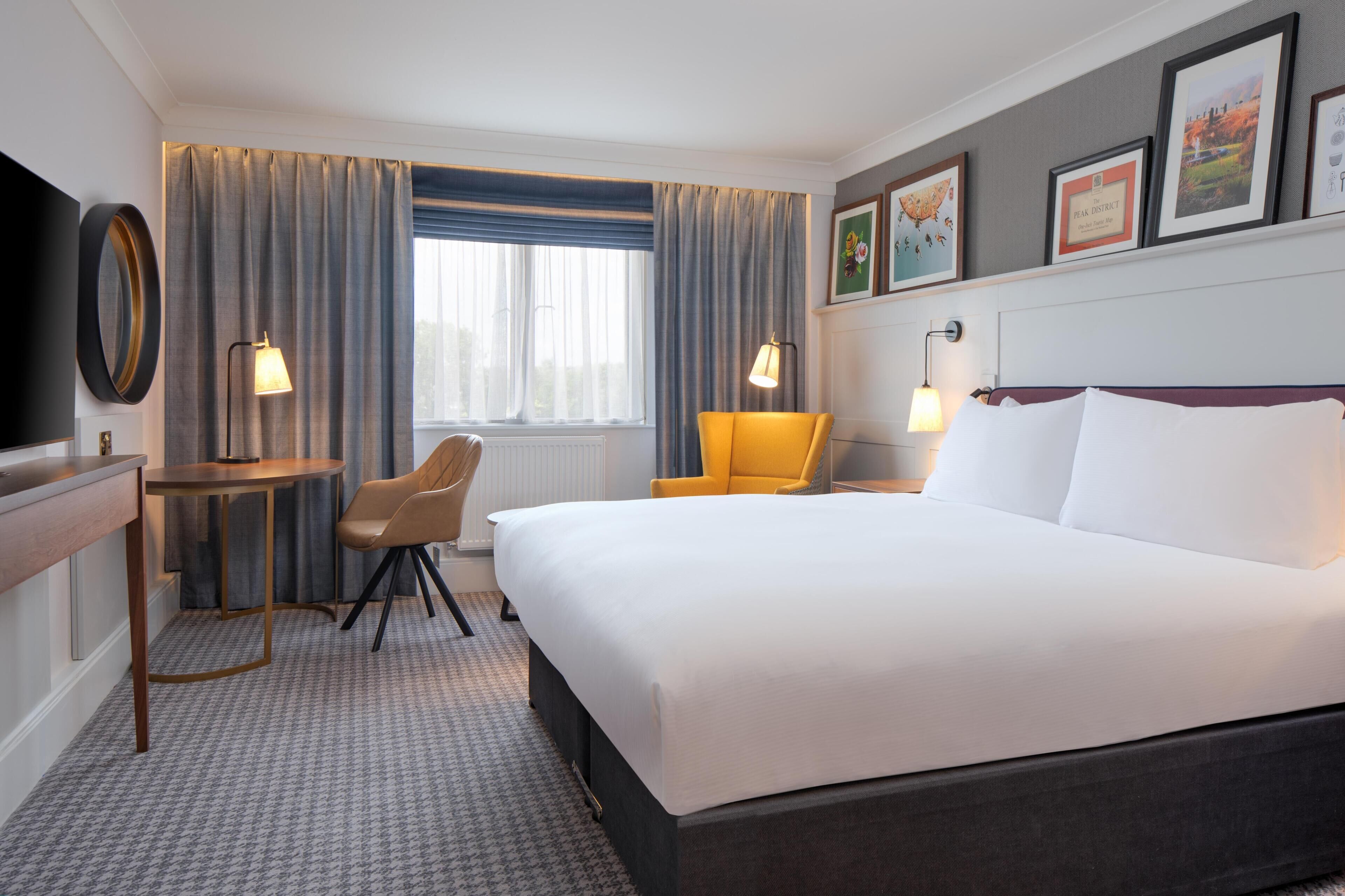 Una habitación de hotel con una cama grande, un escritorio, una silla y un televisor.
