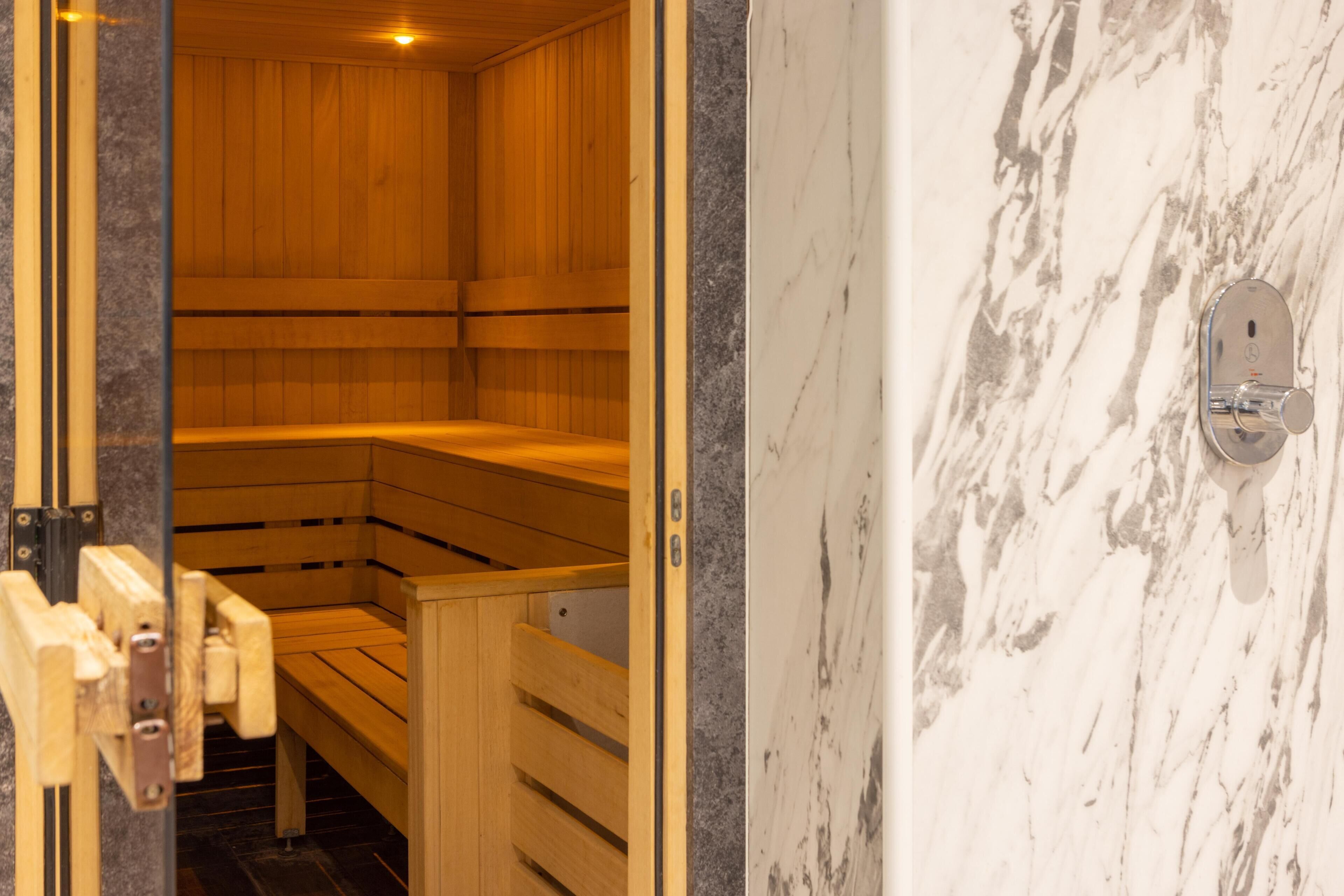 Una sauna con bancos de madera y una pared de mármol.