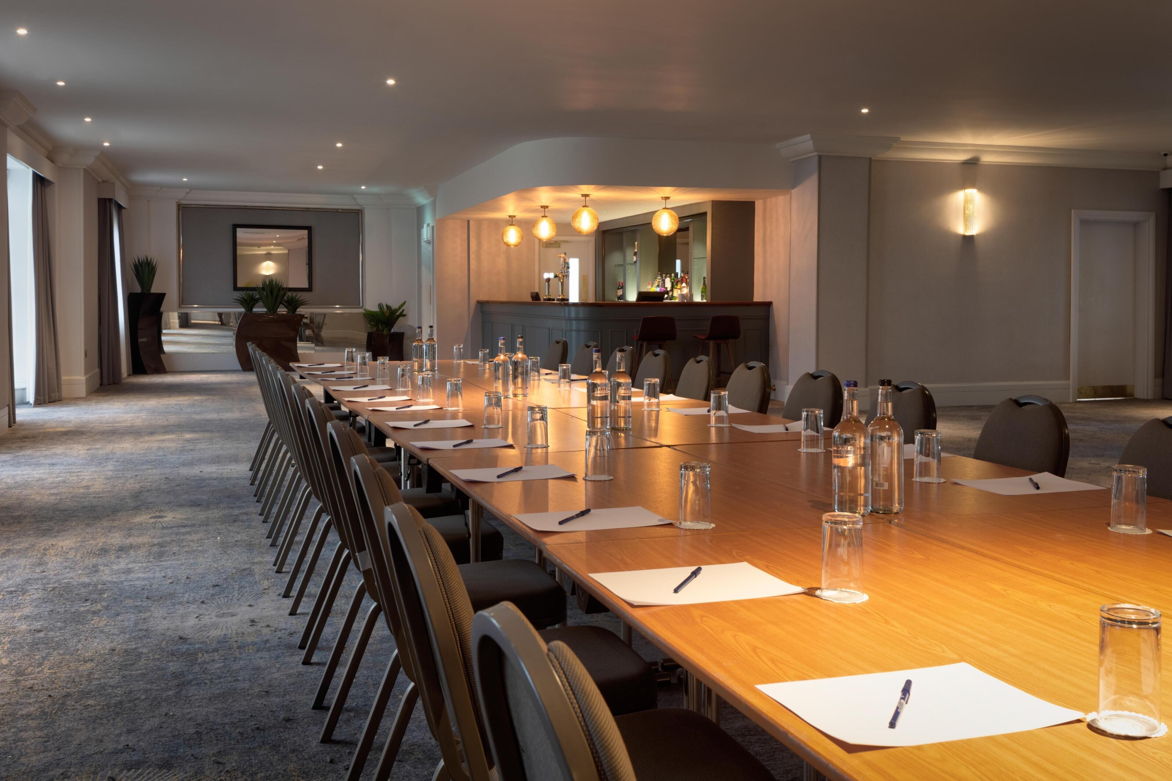 A conference room with a long table, chairs, and a bar area.