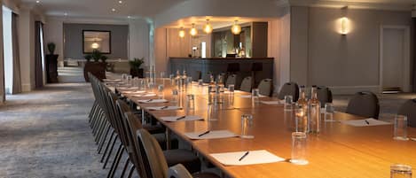 A conference room with a long table, chairs, and a bar area.