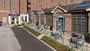 A hotel exterior with a brick facade, outdoor seating area, and a DoubleTree sign. - DoubleTree by Hilton Stoke on Trent (Stoke-on-Trent)