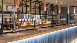 A bar area with multiple taps, shelves of bottles, and glasses. - DoubleTree by Hilton Stoke on Trent (Stoke-on-Trent)