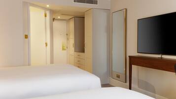 Quarto de hotel com duas camas, televisão, guarda-roupa e espelho.