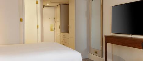 Habitación de hotel con dos camas, televisión, armario y espejo.