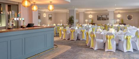 A banquet hall with round tables, white tablecloths, and yellow sashes.