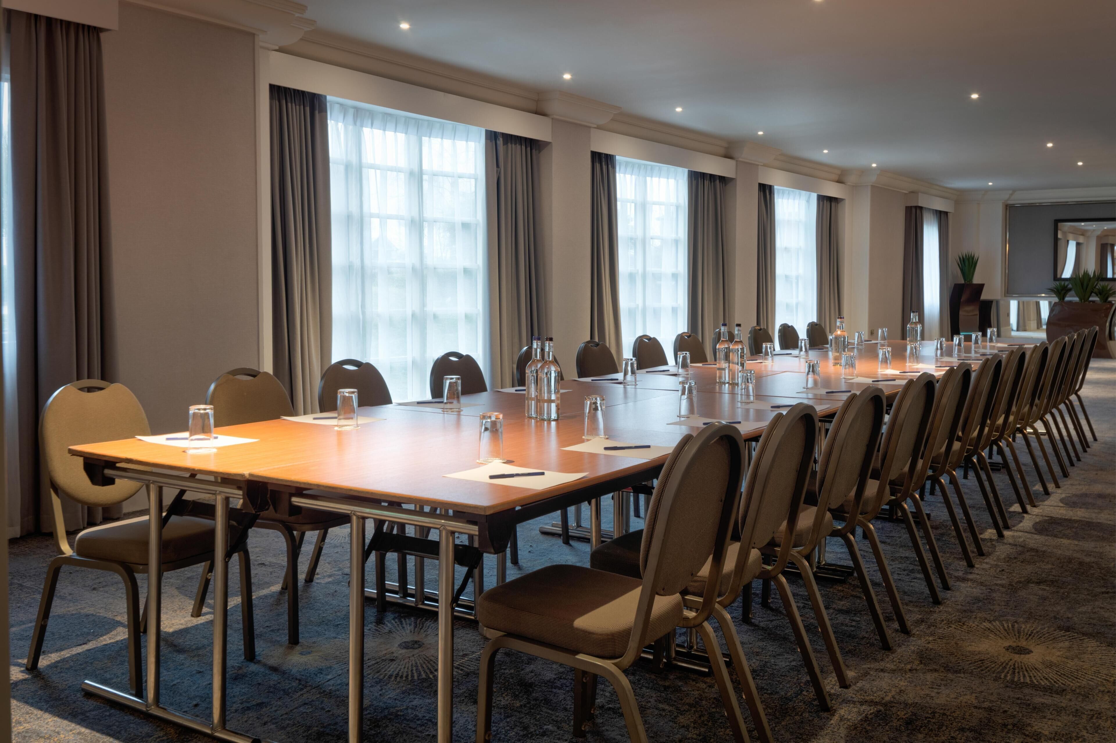 A conference room with a long table, chairs, and large windows.