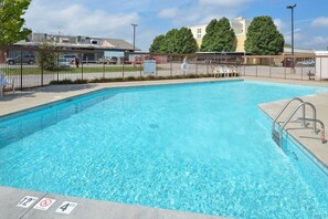 Une piscine rectangulaire à l’eau d’un bleu limpide, entourée d’une clôture en métal, et un poste de surveillance pour les sauveteurs situé sur l’un des côtés.