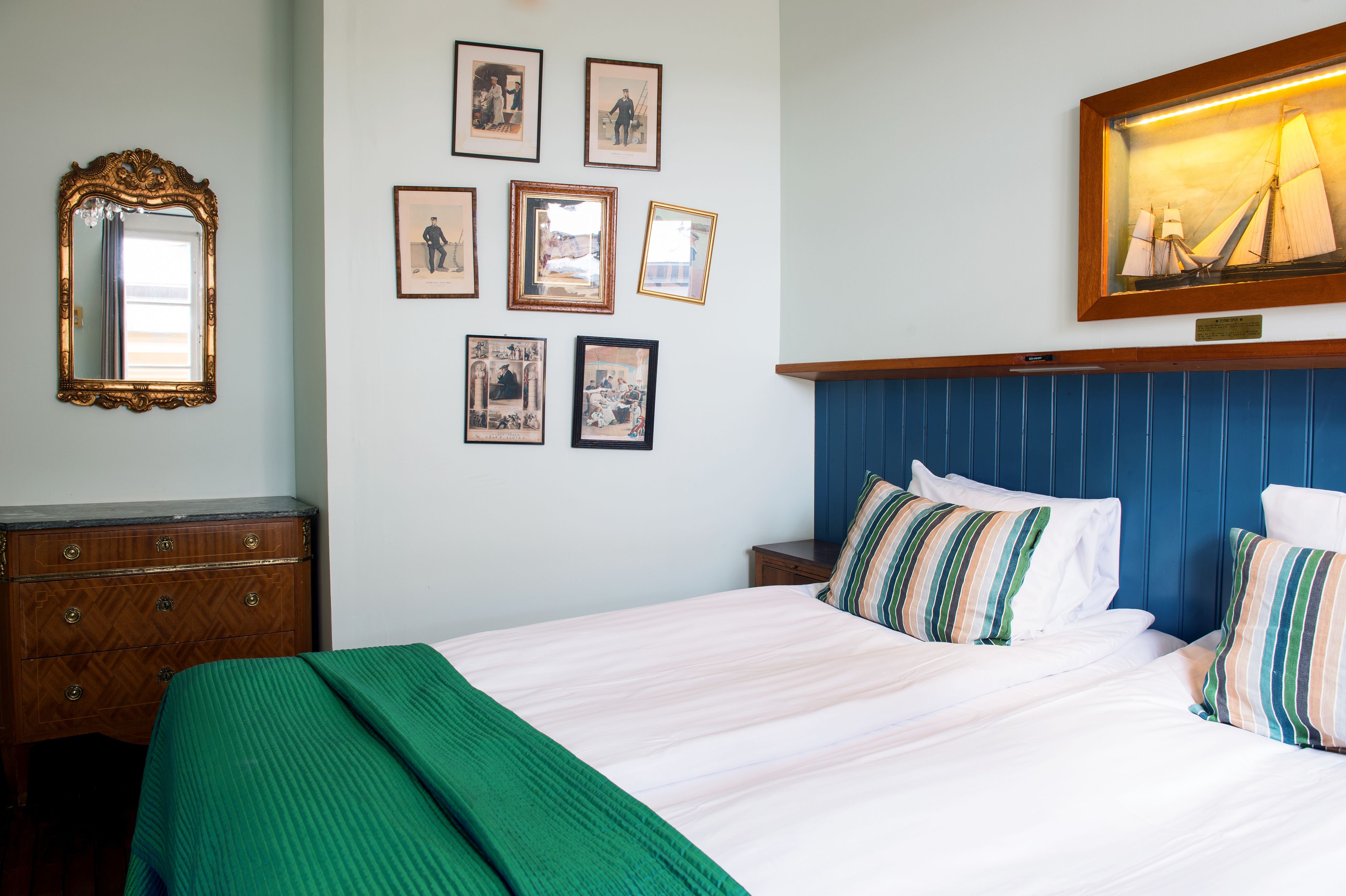 Habitación de hotel con cama, cómoda y pared decorada con cuadros.