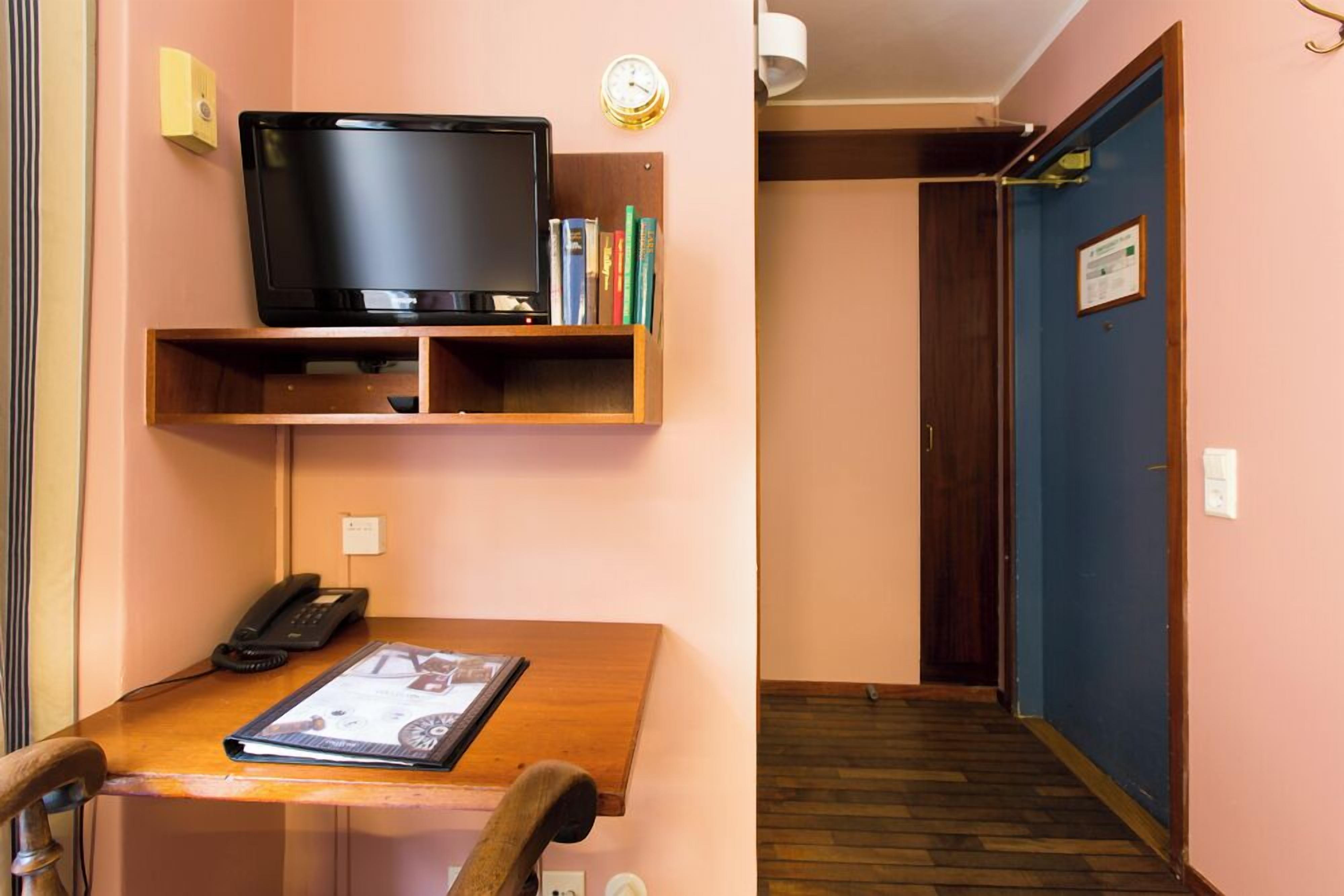 Une chambre d’hôtel avec un bureau en bois, une télévision, une bibliothèque et une porte.