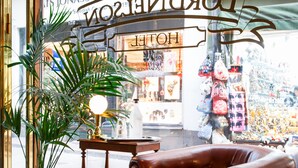 A leather armchair, a potted plant, and a small table with a lamp in front of a shop window with a sign. - Lord Nelson Hotel (Stockholm)