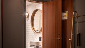 A modern bathroom with a white sink, a mirror, and a wooden door. - Lord Nelson Hotel (Stockholm)