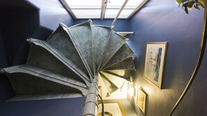 A spiral staircase with a metal handrail in a room with blue walls and a skylight. - Lord Nelson Hotel (Stockholm)