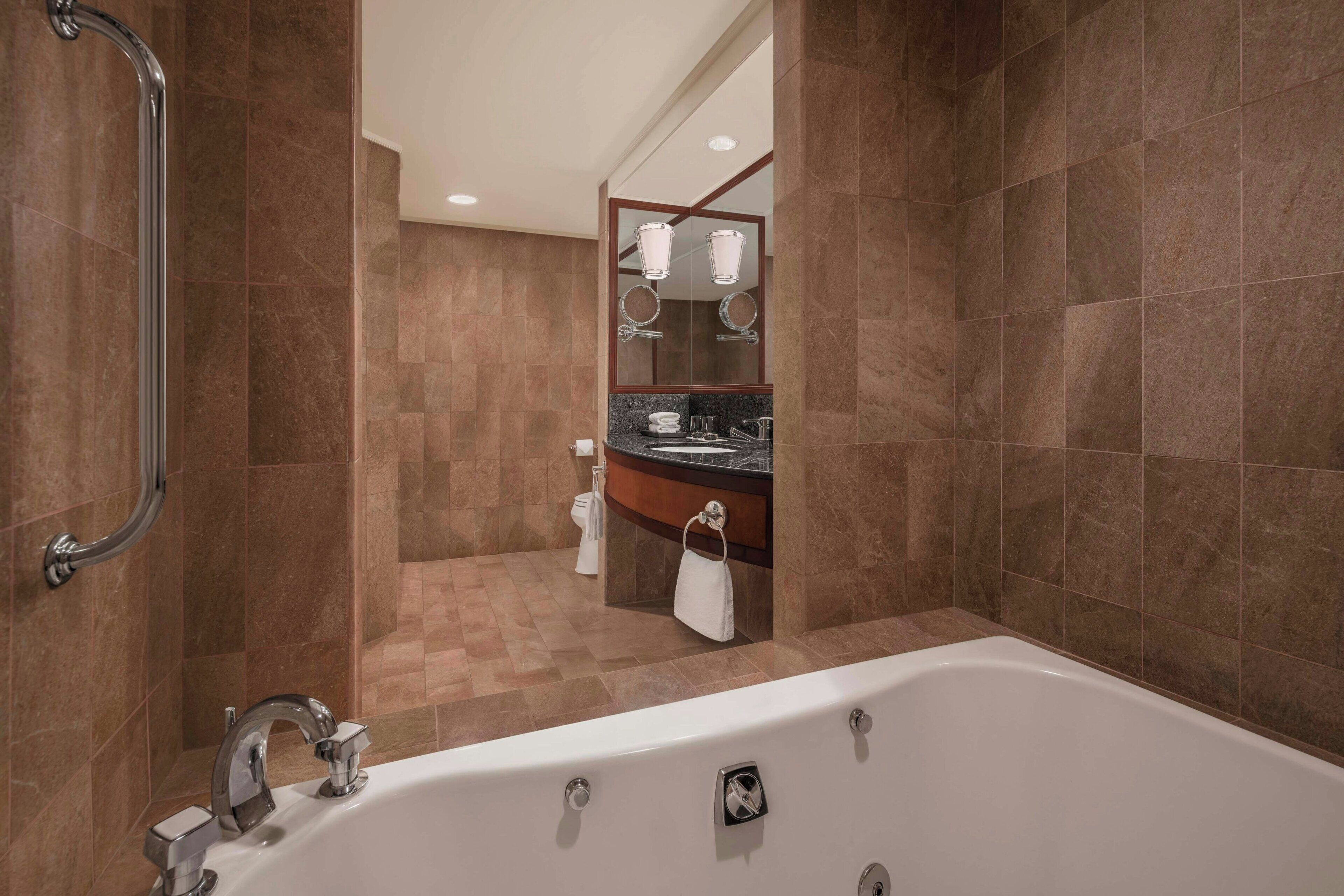 A modern bathroom with a walk-in shower, a bathtub, and a vanity with a mirror.