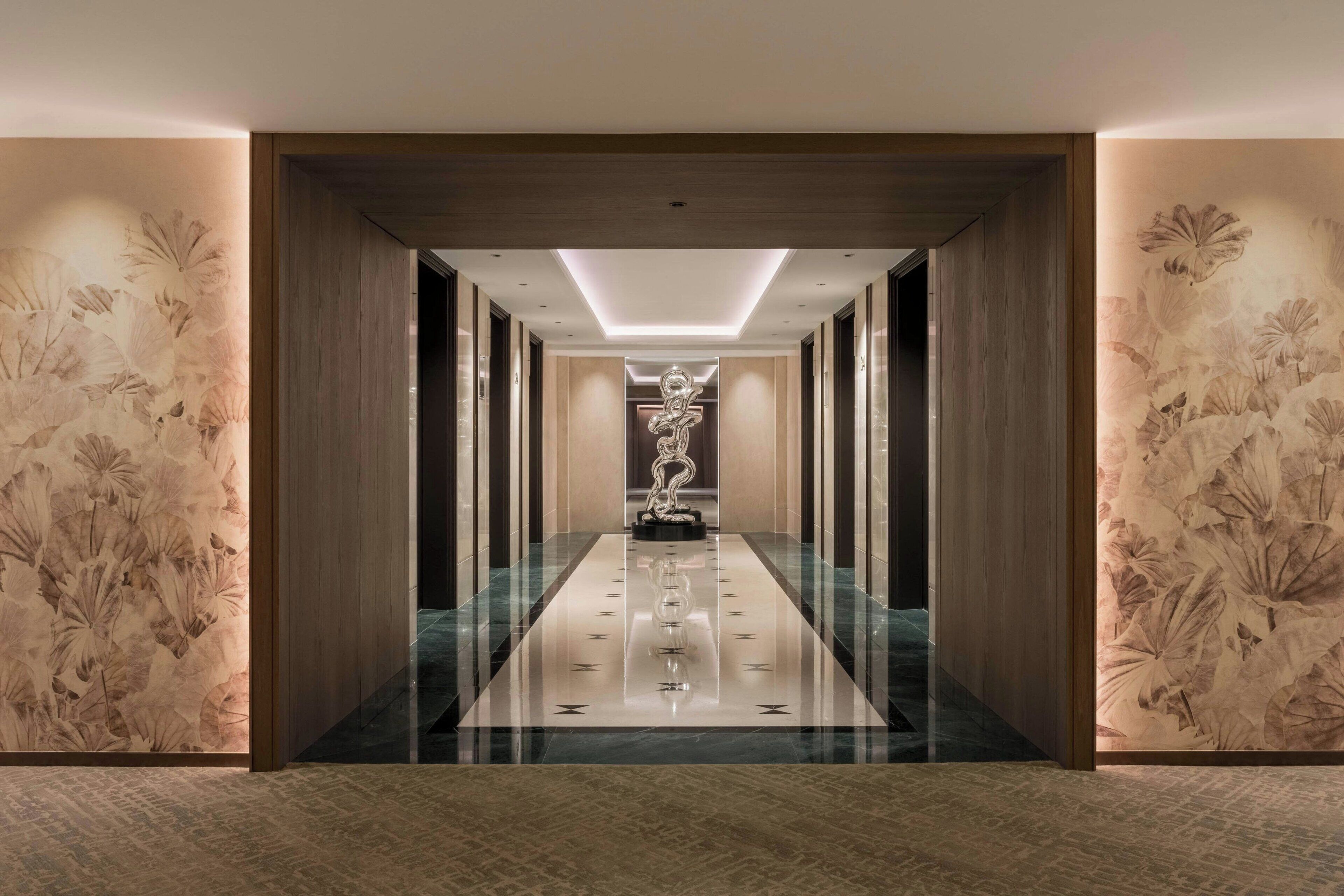 A hallway with a reflective floor, wooden paneling, and floral wallpaper.