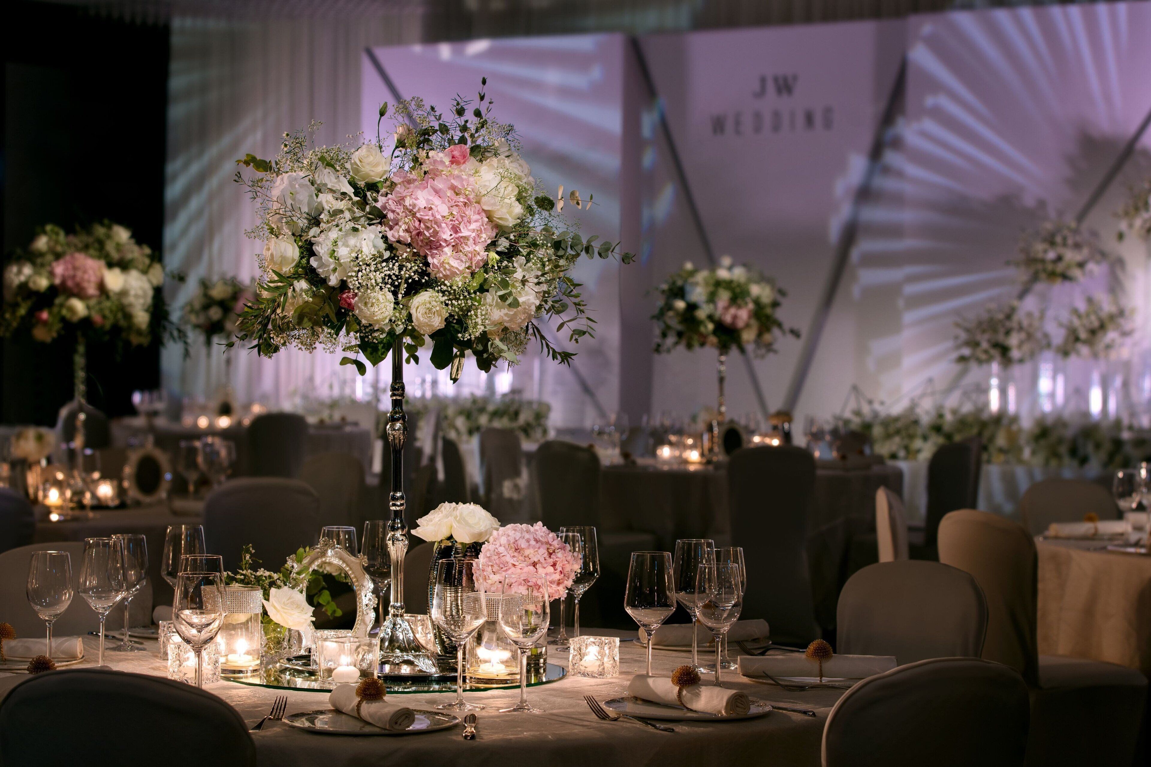 A wedding reception table set with floral centerpieces, candles, and glassware.