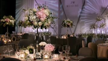 A wedding reception table set with floral centerpieces, candles, and glassware.