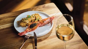Une assiette de pâtes et une crevette cuite sur une table en bois.