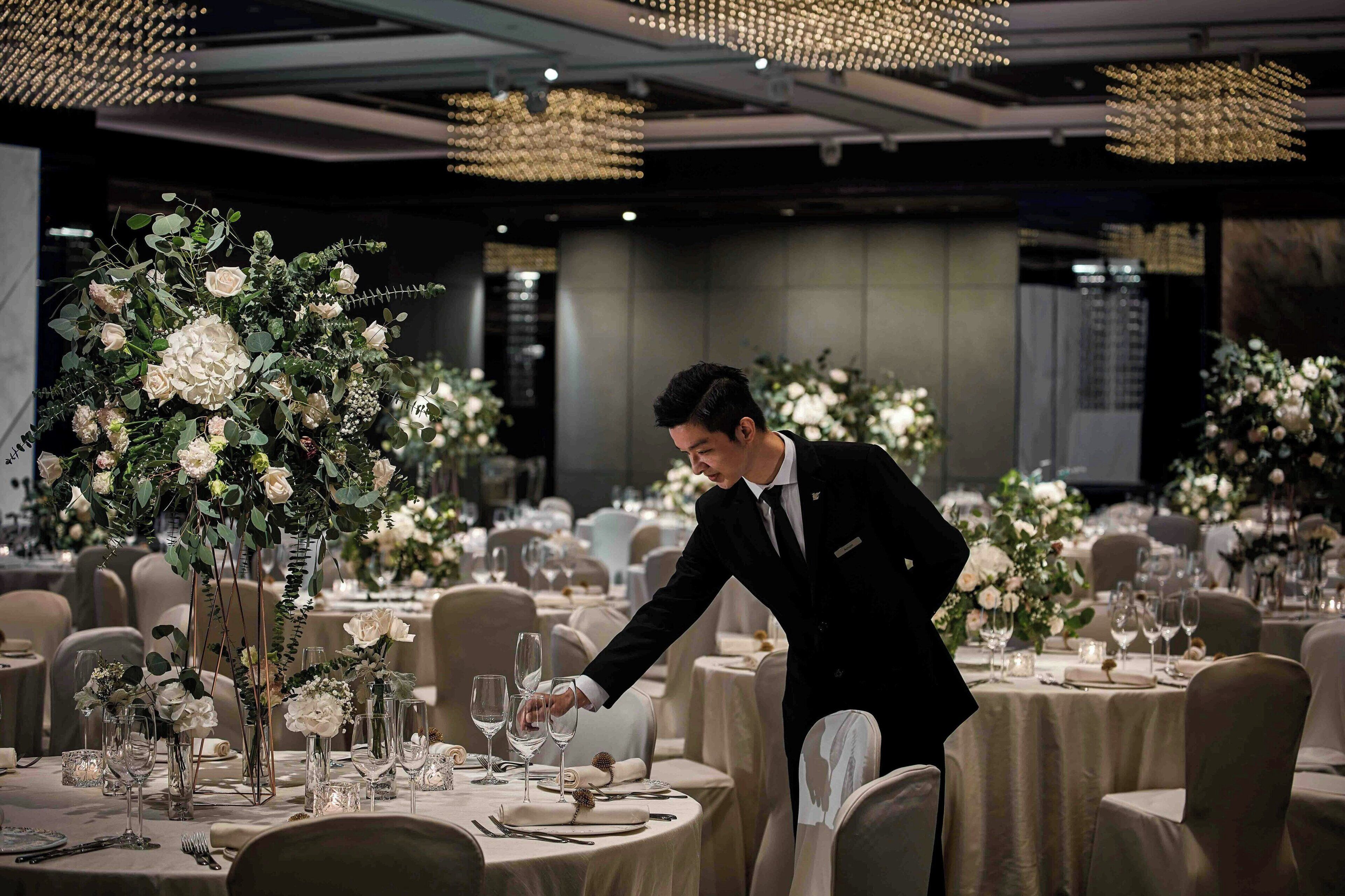 Una elegante disposición para comedor con mesas preparadas para recibir a los invitados, con centros de mesa florales y vajilla distinguida.