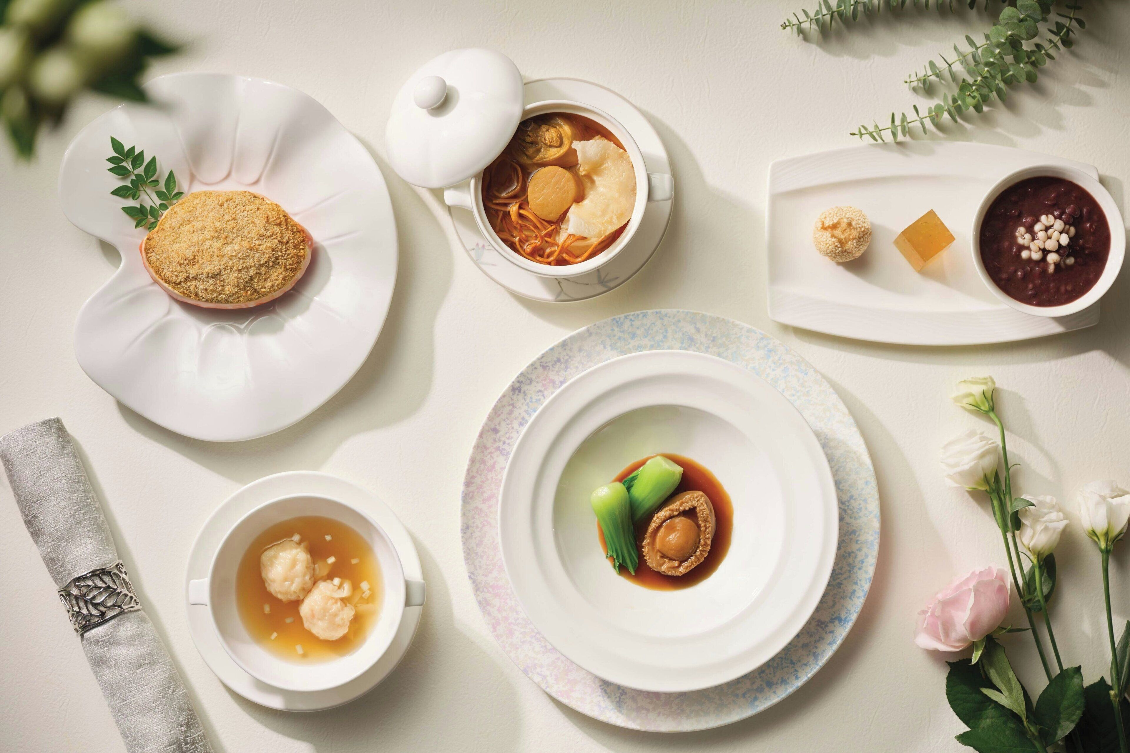 Una mesa con diversos platos, incluyendo un tazón de sopa, un plato con albóndigas y un postre.