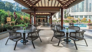 An outdoor patio with wicker furniture, a pool, and a view of a cityscape. - JW Marriott Hotel Hong Kong (Hong Kong)