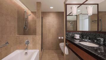 Un baño moderno con bañera, lavamanos, tocador, ducha y un espejo grande.