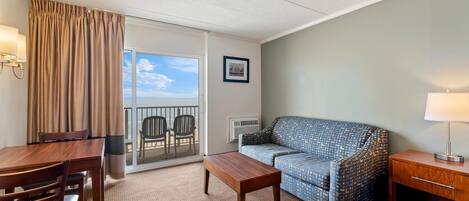 Une chambre d’hôtel avec un balcon, un canapé, une table à manger et une lampe.
