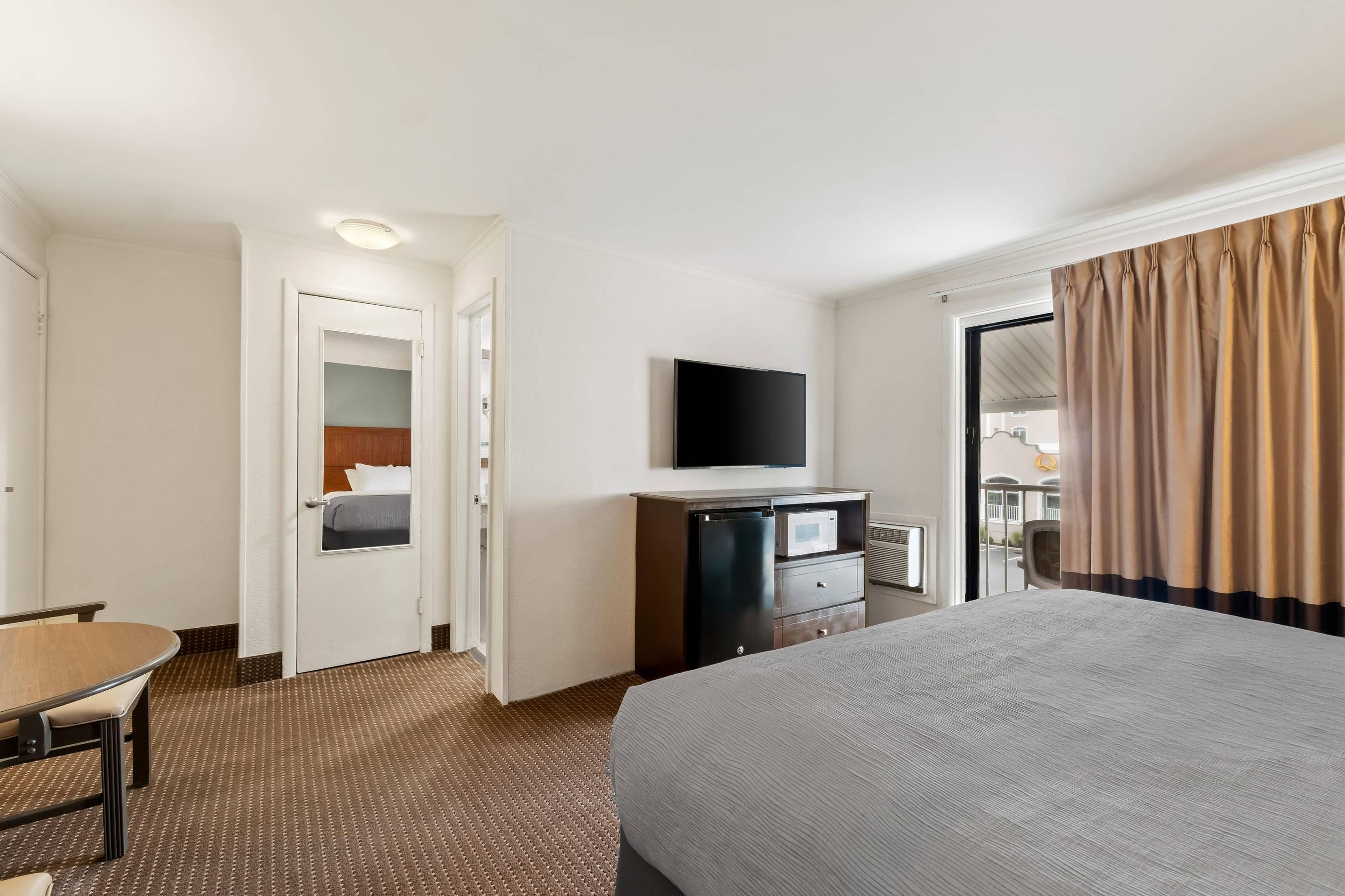 Une chambre d’hôtel équipée d’un lit, d’un bureau, d’une télévision, d’un mini-bar et offrant une vue sur l’extérieur.