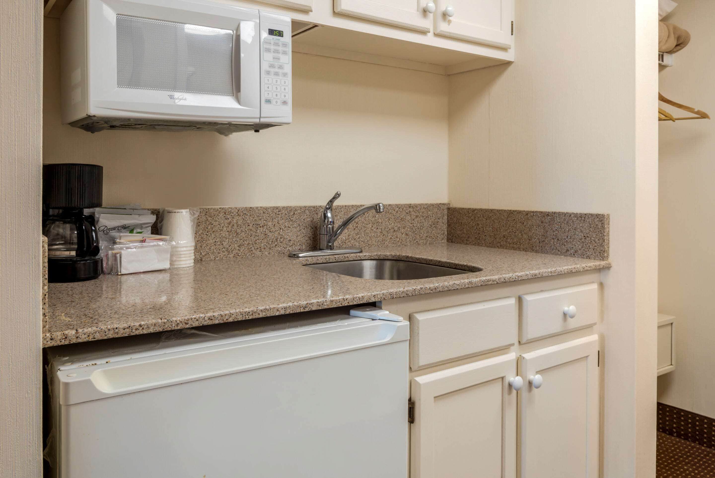 Una cocina compacta con microondas integrado, pileta de acero inoxidable y lavavajillas.