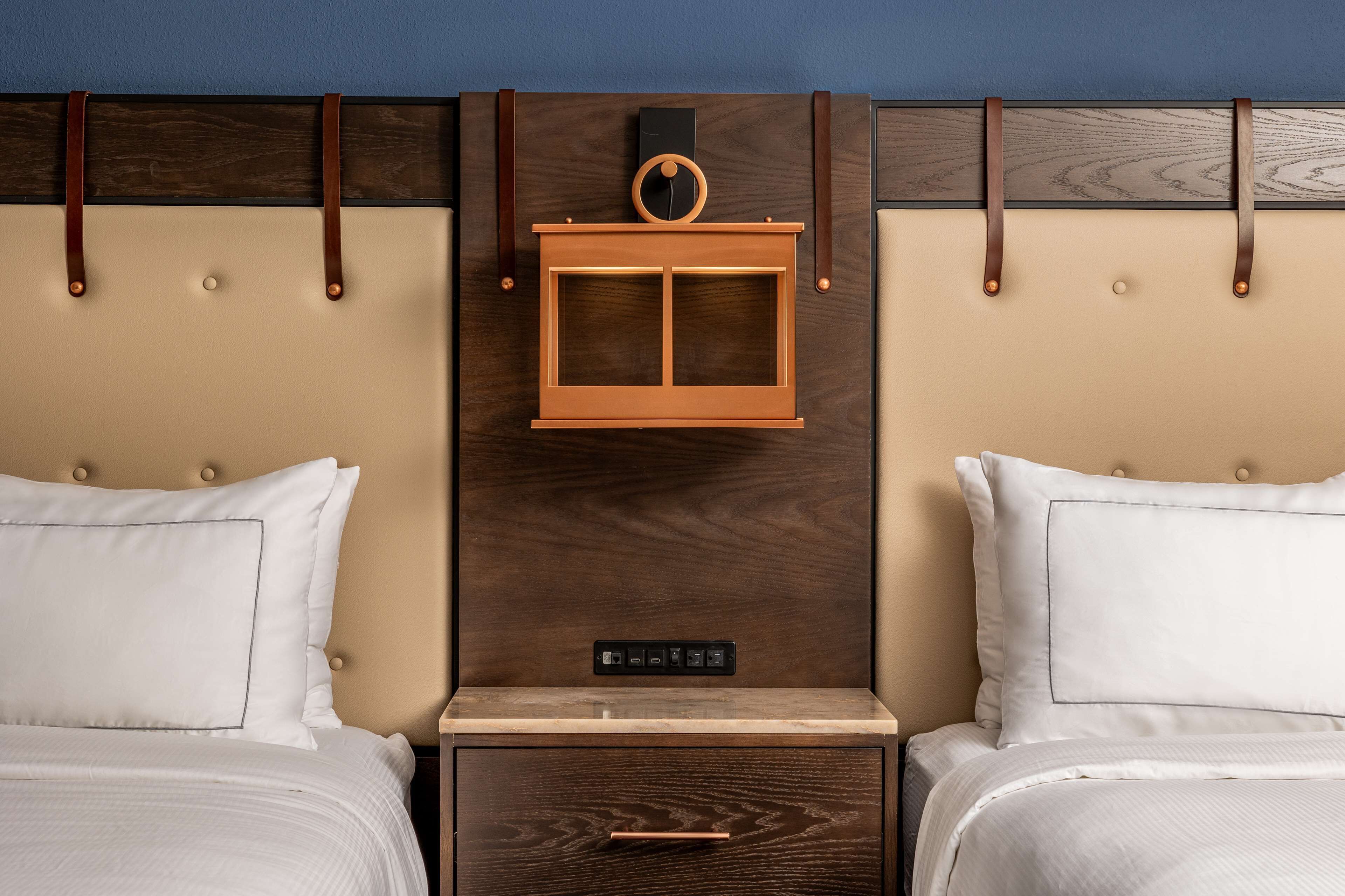 Un lit double avec une tête de lit en bois, une petite étagère en bois et une table de chevet avec un tiroir.
