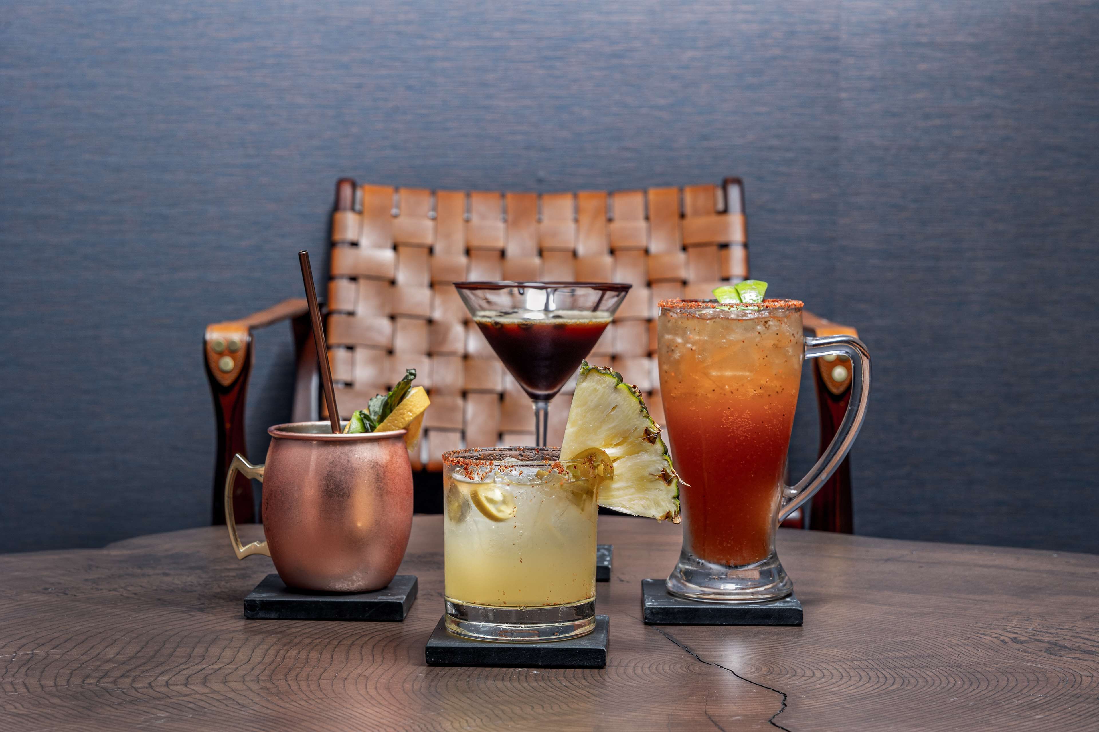 Tres bebidas sobre una mesa de madera, con una silla de mimbre al fondo.
