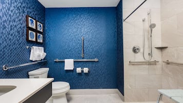 Een badkamer met een blauw behang, een wit toilet, een wastafel, een douche en een handgreep.