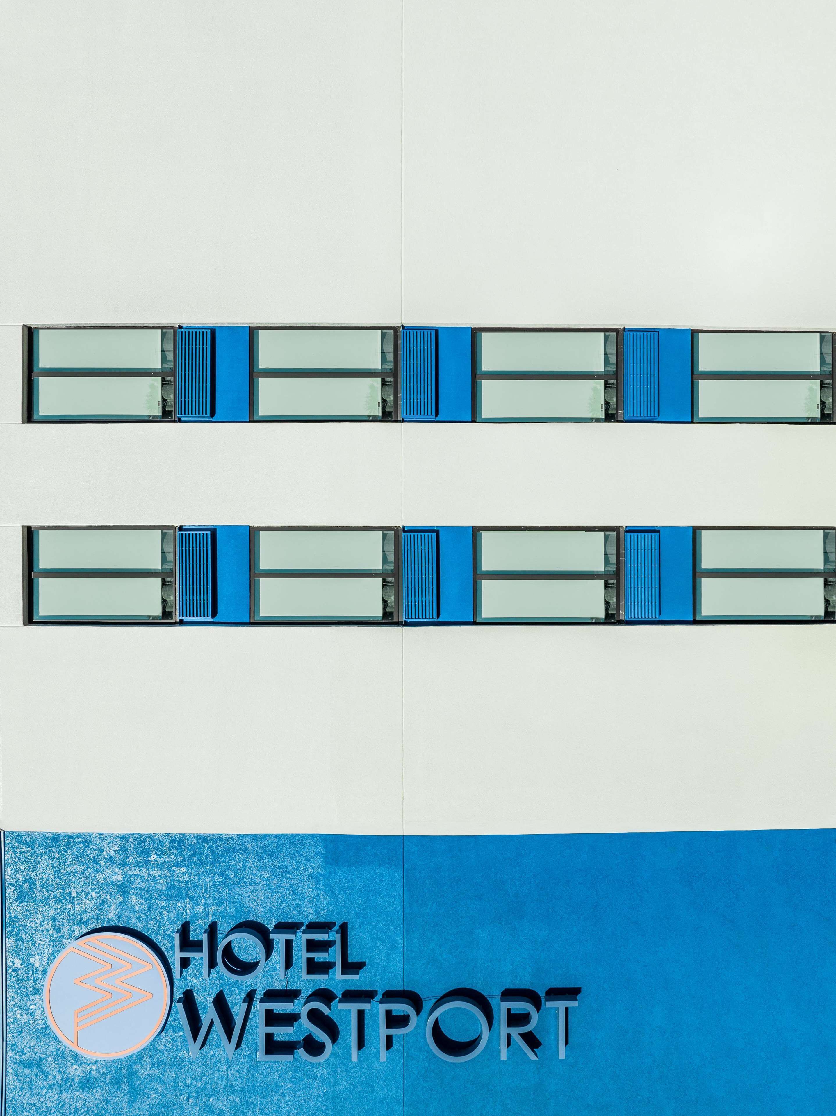 Un hôtel au design moderne, dont la façade est ornée d’un logo bien visible et du nom « HOTEL WESTPORT ».