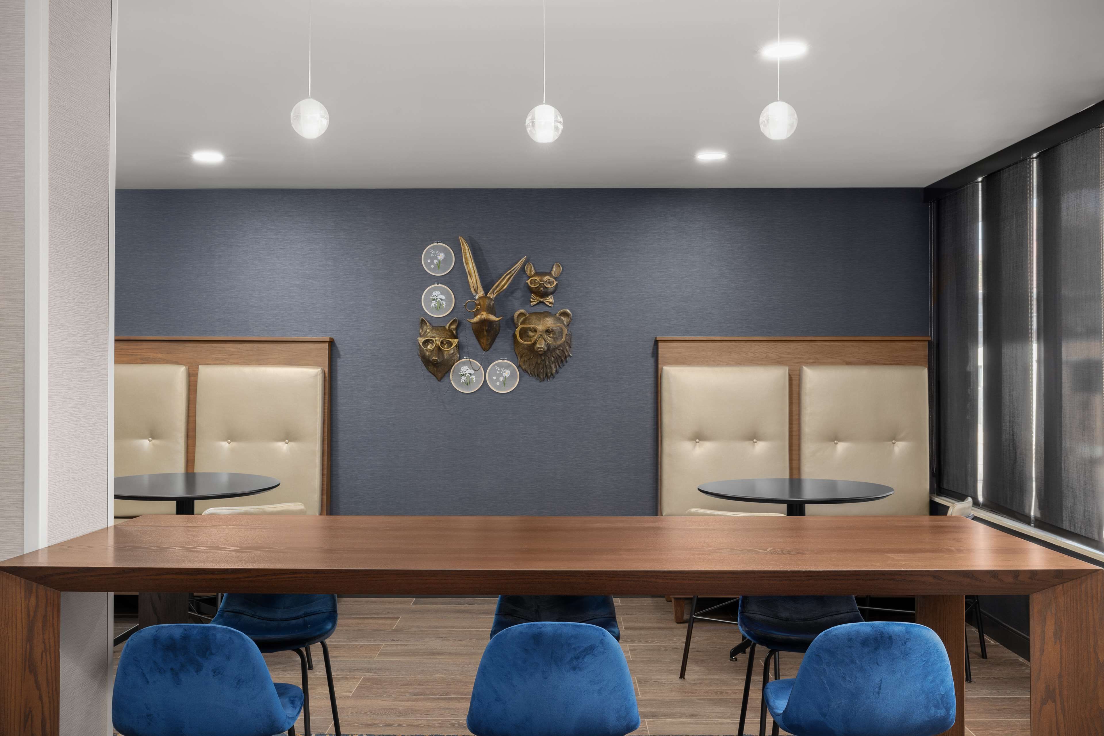 A conference room with a long wooden table, blue chairs, and a wall-mounted decorative piece.