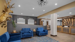 A reception area with blue sofas, a patterned carpet, and a decorative deer head.