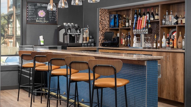A bar area with stools, a coffee machine, and a variety of liquor bottles.