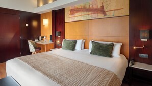 A hotel room with a large bed, a desk, and a chair.
